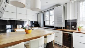 Een moderne keuken met witte kastjes, een houten kookeiland en een inbouw vaatwasser.