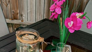Una mesa de vidrio con dos copas de vino, una cesta tejida y una orquídea rosa. Un letrero de bienvenida está colocado sobre la mesa.