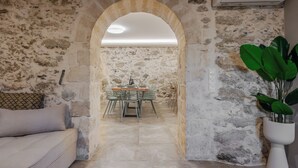Habitación de paredes de piedra con zona de comedor, un sofá y una planta en maceta.