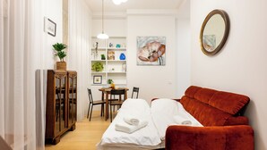 A compact room with a bed, a red sofa, a dining table, and a bookshelf. - Spacious & Quiet Apt with Terrace 1-BR, Riga Centre (Rīga)