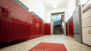 A hallway with red lockers, a red carpet with "RIGA SCHOOLHOUSE & LOFTS" text, and a staircase leading to another area. - Spacious & Quiet Apt with Terrace 1-BR, Riga Centre (Rīga)