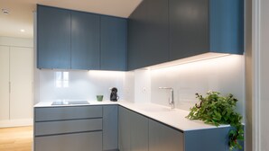 Una cocina moderna con armarios azules, encimera blanca y un lavamanos.