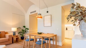 Un salon moderne avec un canapé, une table à manger et des chaises, une lampe et une plante en pot.