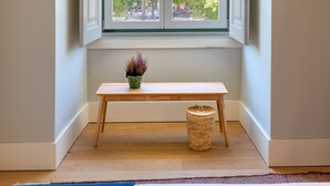Une pièce dotée d’une grande fenêtre, d’un banc et d’une petite table sur laquelle est posée une plante.