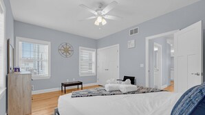 Une chambre à coucher avec un lit, un bureau, une chaise et un ventilateur de plafond.