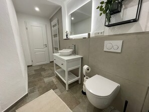 Une salle de bain moderne avec un lavabo blanc, des toilettes et un porte-serviettes.
