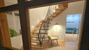 Un escalier avec des marches en bois et des rampes en métal menant à un espace situé au deuxième étage.