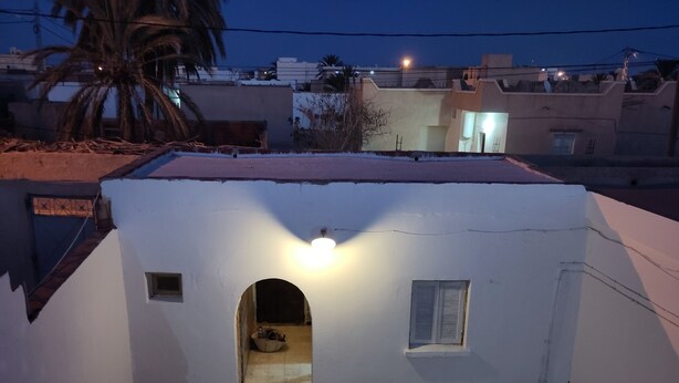 Un pequeño edificio de paredes blancas con una sola ventana y una entrada en arco.