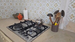 Una cocina con estufa a gas, una olla, un hervidor y un recipiente para utensilios.