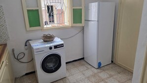 Pequeña lavandería con lavadora y refrigerador.