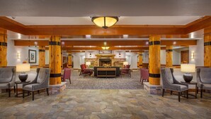 A spacious lobby with stone flooring, wooden pillars, and a central seating area with a fireplace. - WorldMark West Yellowstone condo with easy access to Yellowstone West Gate. (West Yellowstone)