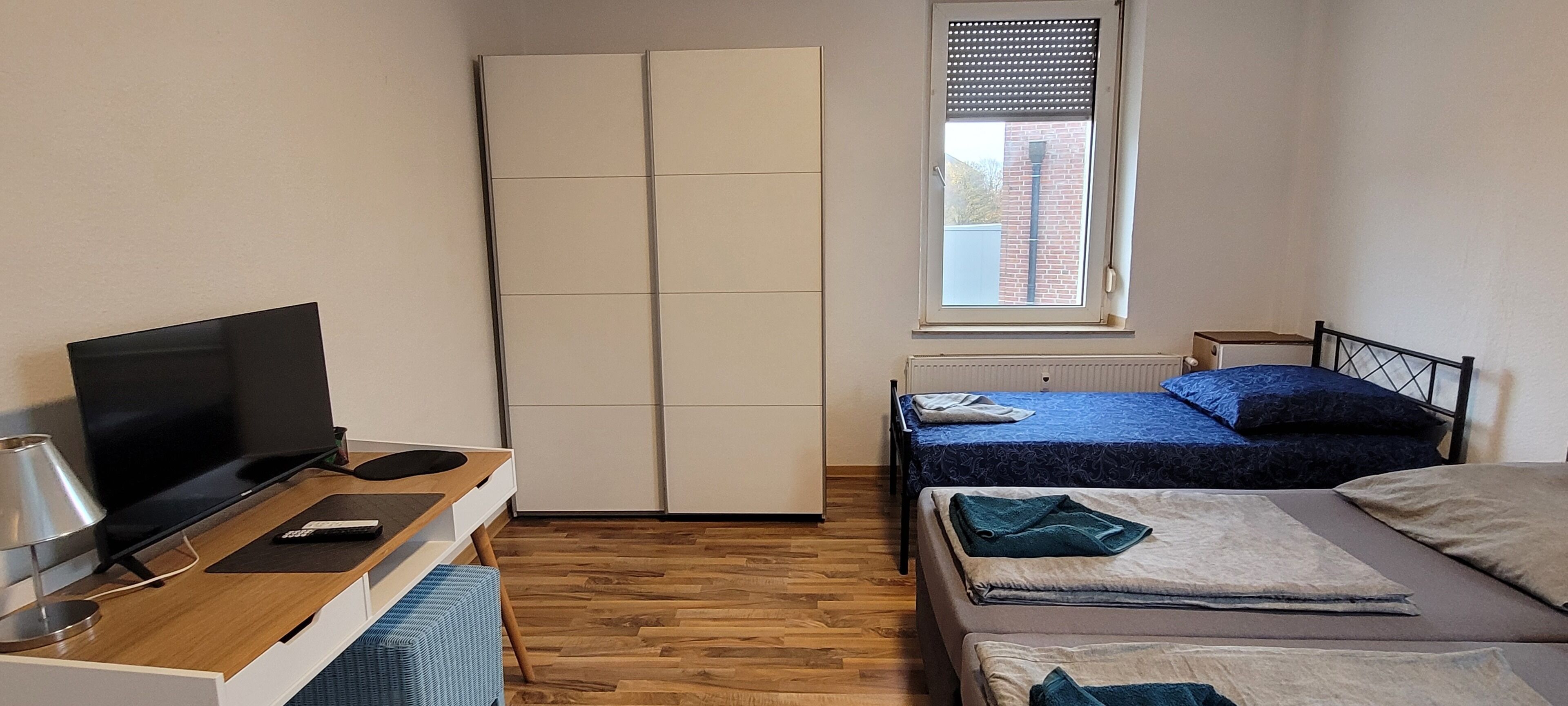 Een slaapkamer met een televisie, een kledingkast, een bed en een raam.