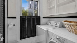 A laundry room with a washing machine, dryer, and a window with shutters. - Historic Mystic Maritime House - 5 min Walk to Downtown Restaurants and Seaport (Mystic)