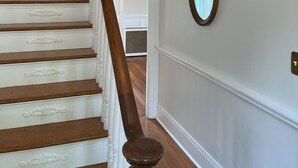 Eine Treppe mit aufwendiger weißer Geländer und einer Holzhandläufe, die zu einem Raum mit einem großen Spiegel an der Wand führt.