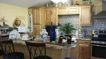 A kitchen with wooden cabinets, a granite countertop, and a sign advertising free range eggs for sale.