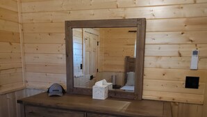 Interior de una cabaña de madera con un aparador, un espejo y una puerta.