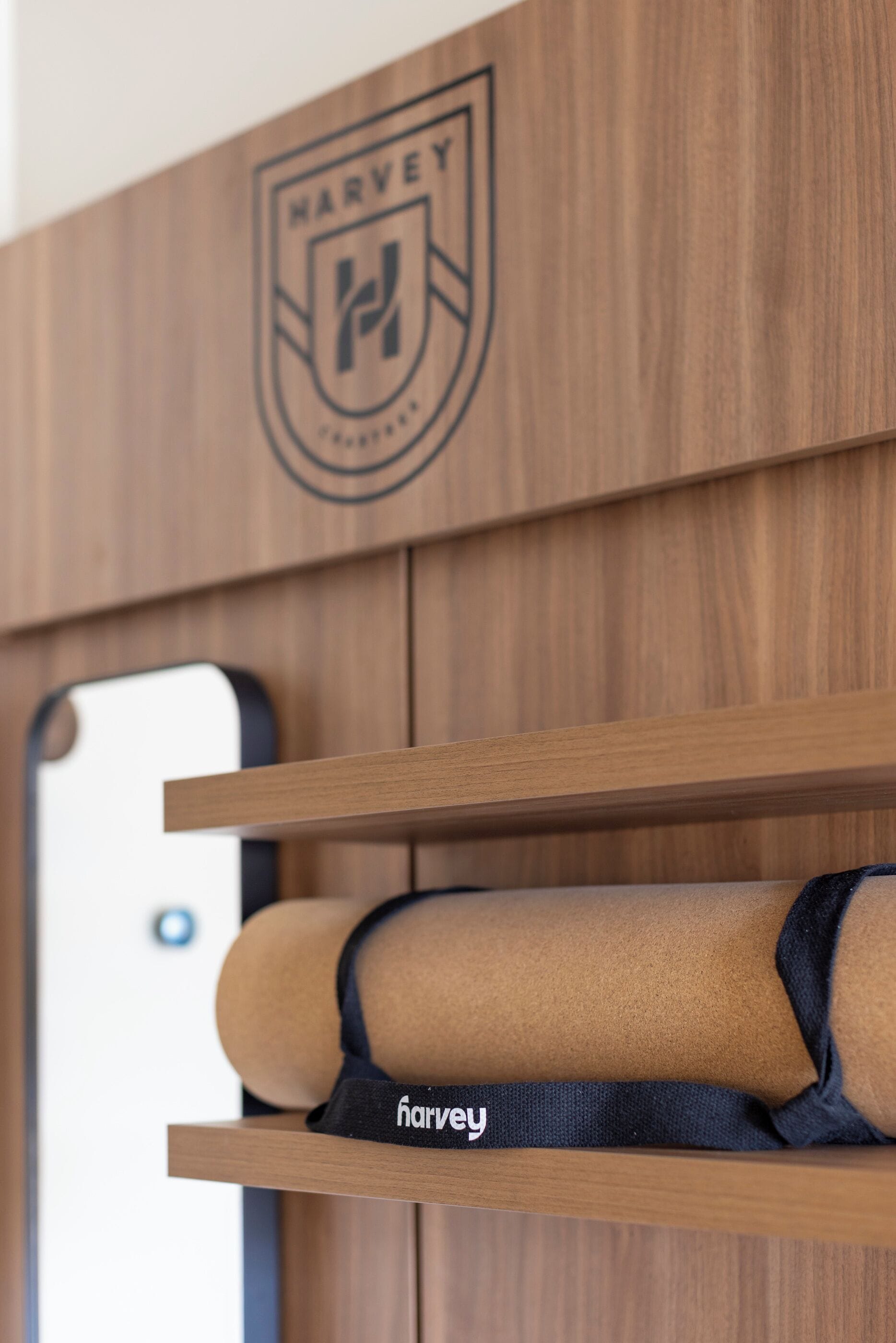 A wooden wall with a logo and a smartphone on a stand.