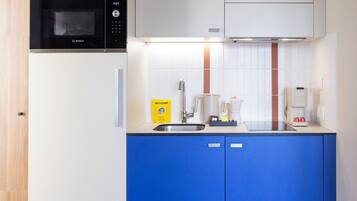 Uma cozinha moderna com armários brancos, micro-ondas preto e bancada azul.