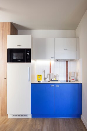 Une cuisine moderne avec des meubles blancs, un micro-ondes noir et un plan de travail bleu.