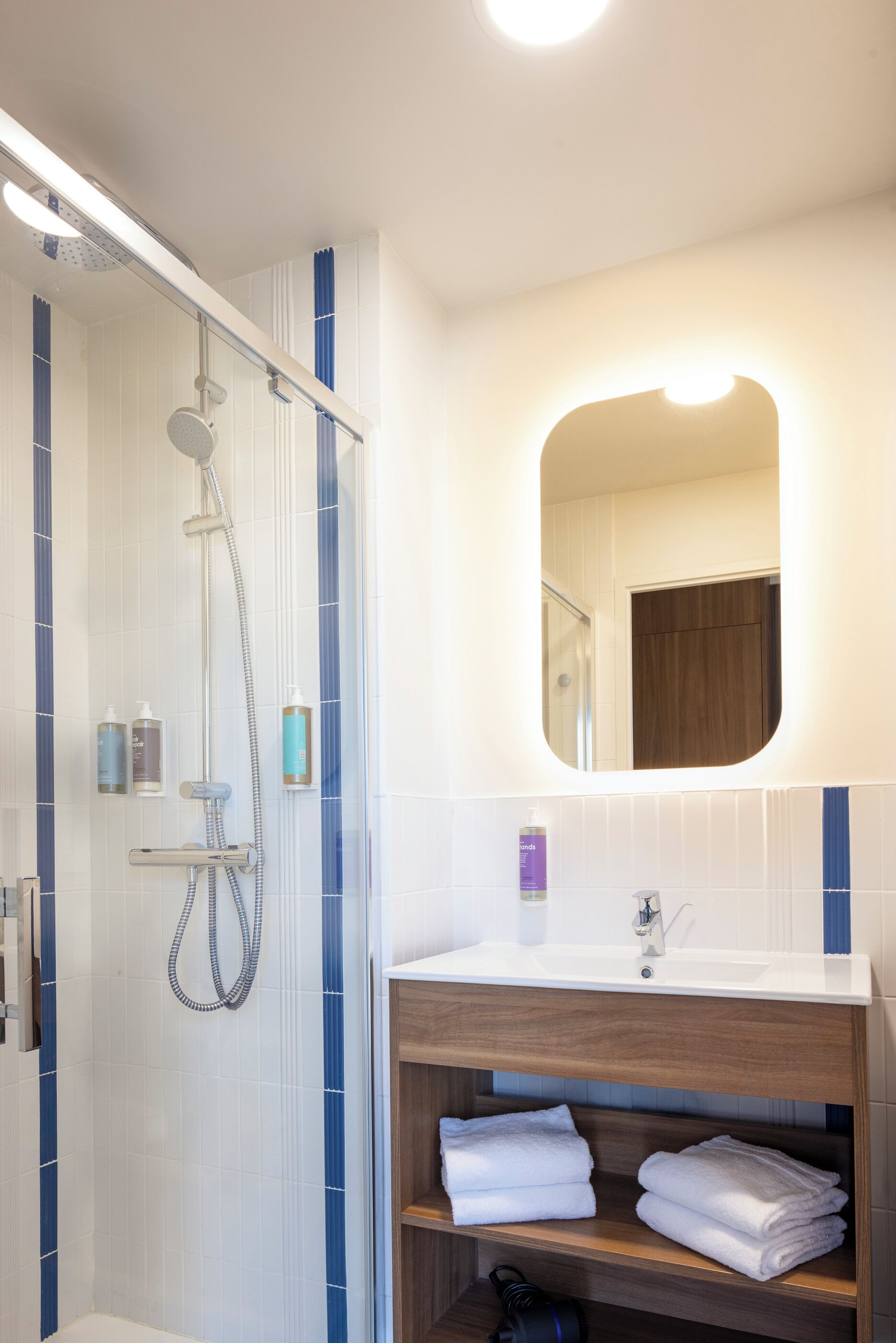 Een moderne badkamer met een douche, een wastafel en een spiegel.