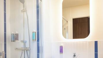 Een moderne badkamer met een douche, een wastafel en een spiegel.