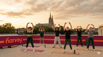 Um grupo de pessoas praticando yoga em um terraço, com uma igreja ao fundo.