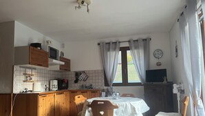 A kitchen with wooden cabinets, a microwave, and a dining table with chairs. - Cosy Studio 4 people - Valmorel hamlet (Les Avanchers-Valmorel)