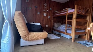 A room with wooden walls, a bunk bed, a cushioned chair, and a small rug. - Cosy Studio 4 people - Valmorel hamlet (Les Avanchers-Valmorel)