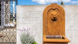 A stone wall with a lion head sculpture and a small fountain.