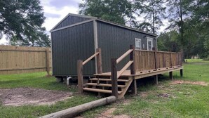 Un petit abri en bois sombre, avec un escalier en bois menant à une plateforme.
