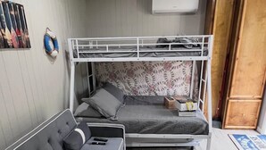 Un lit superposé avec une tête de lit à motifs, un canapé avec des coussins et une petite table avec un coffre.
