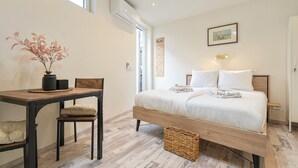 Ein Schlafzimmer mit Bett, Nachttisch, Sessel und einem kleinen Tisch mit einer Vase.