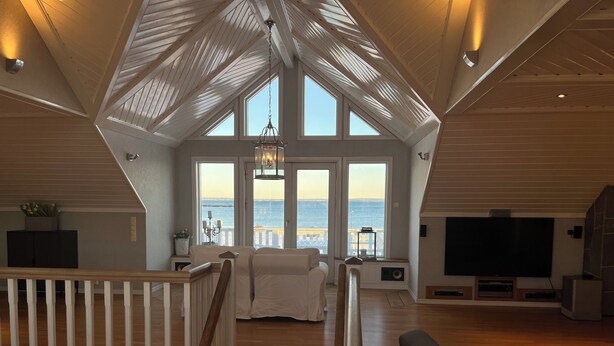 A spacious living area with a high ceiling, large windows, and a view of the sea. - First-Row Beachfront Villa with Stunning Views - Sleeps 16 people+ (Vestfold)