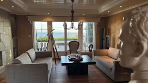 A spacious living room with a large window overlooking the sea, a stone fireplace, and a modern chandelier. - First-Row Beachfront Villa with Stunning Views - Sleeps 16 people+ (Vestfold)