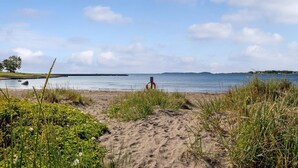 A beach with a sandy path leading to the water, a lifeguard tower, and distant landforms. - First-Row Beachfront Villa with Stunning Views - Sleeps 16 people+ (Vestfold)