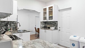 A modern kitchen with white cabinets, a marble countertop, and a ceiling fan. - Stylish 2BR/2BA Home near Wynwood (Miami)
