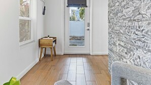 A hallway with a wooden floor, a door with a view to the outside, and a textured wall. - Stylish 2BR/2BA Home near Wynwood (Miami)