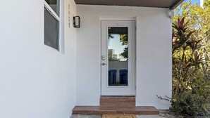A white door with a glass panel, a small step leading up to it, and a doormat with the word "welcome". - Stylish 2BR/2BA Home near Wynwood (Miami)