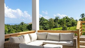 Un balcone con un divano in vimini e un traliccio in legno.