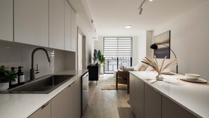 A modern kitchen with a built-in sink, a dining area with a bench, and a large window with blinds.