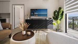 A modern living room with a flat-screen TV, a large plant, and a view of the city through the balcony.