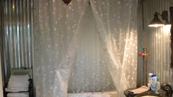 A bedroom with a canopy bed, a bedside table, a mirror, and a bathroom with a sink and toilet.