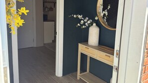 A hallway with a dark blue wall, a wooden console table with a mirror, and a vase with white flowers. - Cozy 1-bedroom studio in gorgeous El Paso (El Paso)