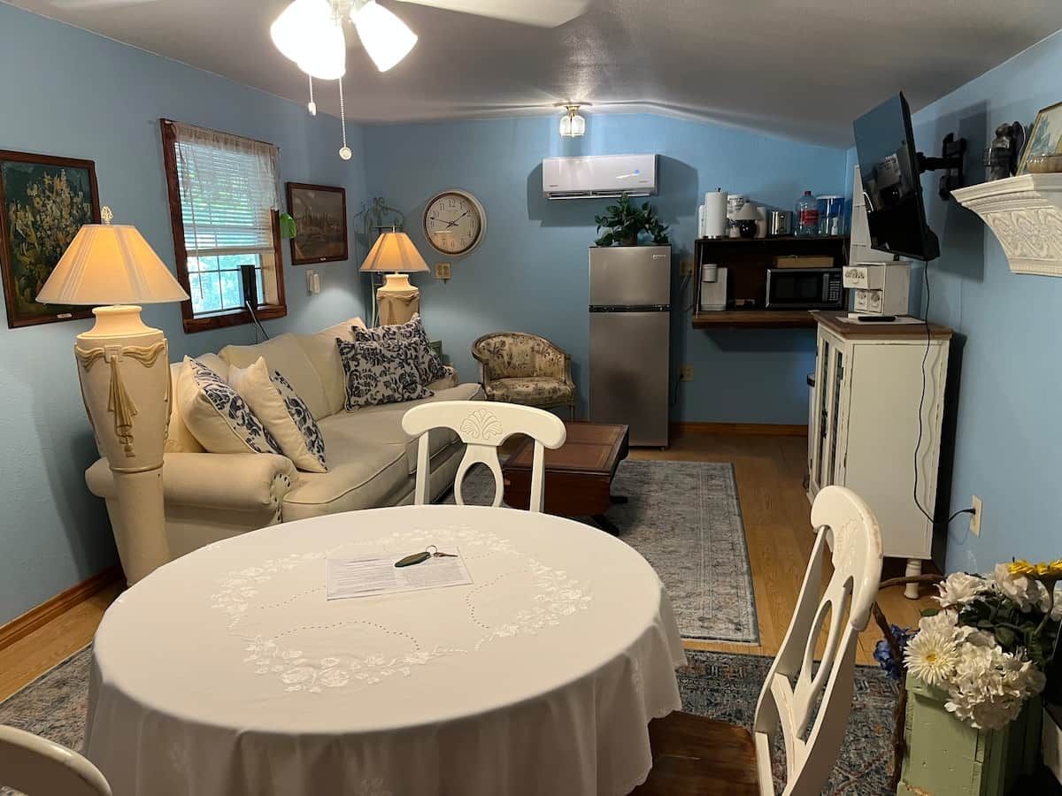 A living room with a dining table, a sofa, a TV, and a refrigerator.