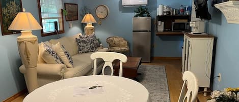 A living room with a dining table, a sofa, a TV, and a refrigerator.