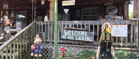 Une cabane rustique avec une véranda en bois, une pancarte de bienvenue et une nichoir.