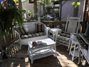 A wooden deck with wicker furniture, including a sofa and chairs, and a small table.
