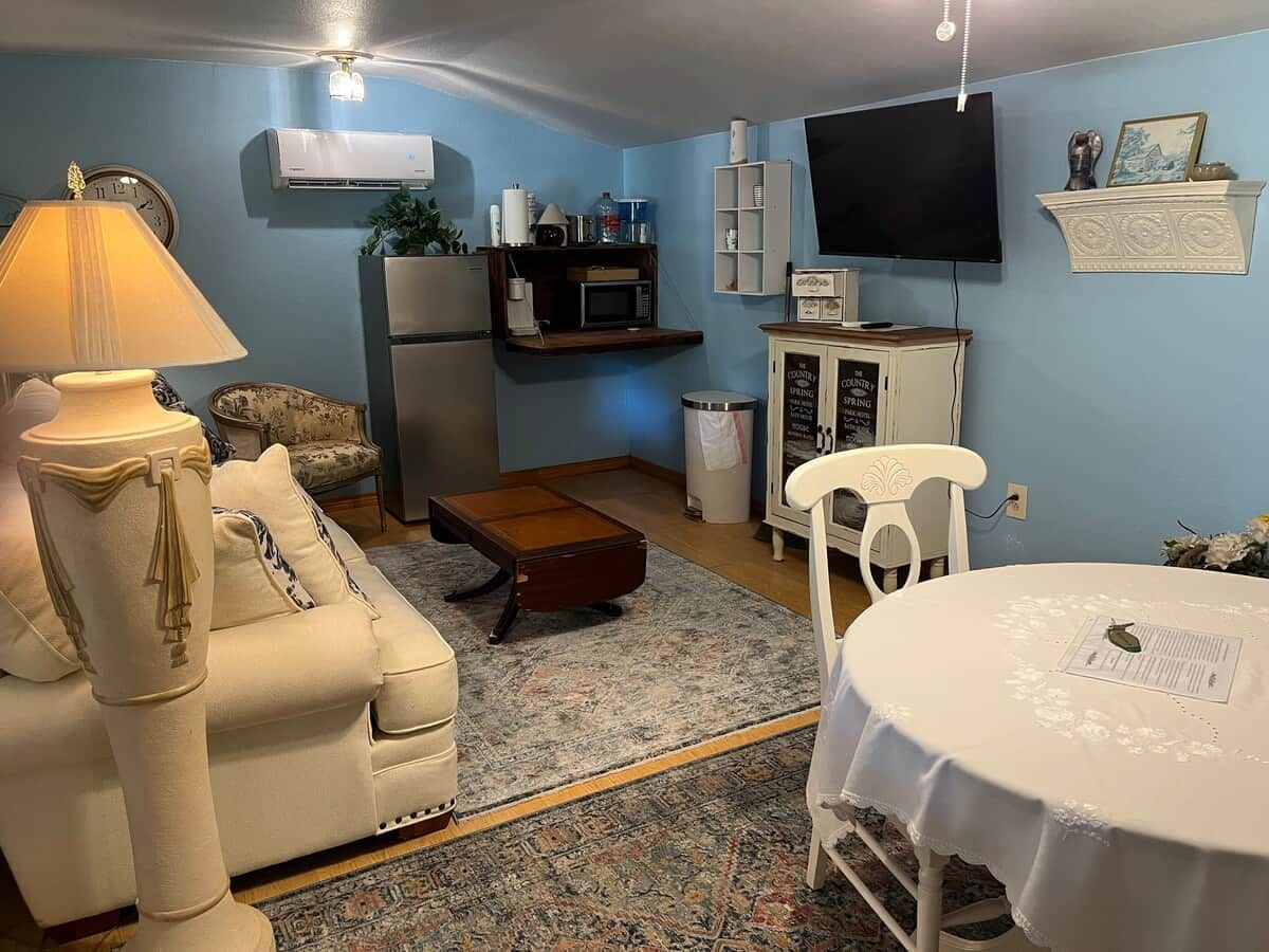 A living room with a sofa, armchair, coffee table, and a dining table with a placemat.