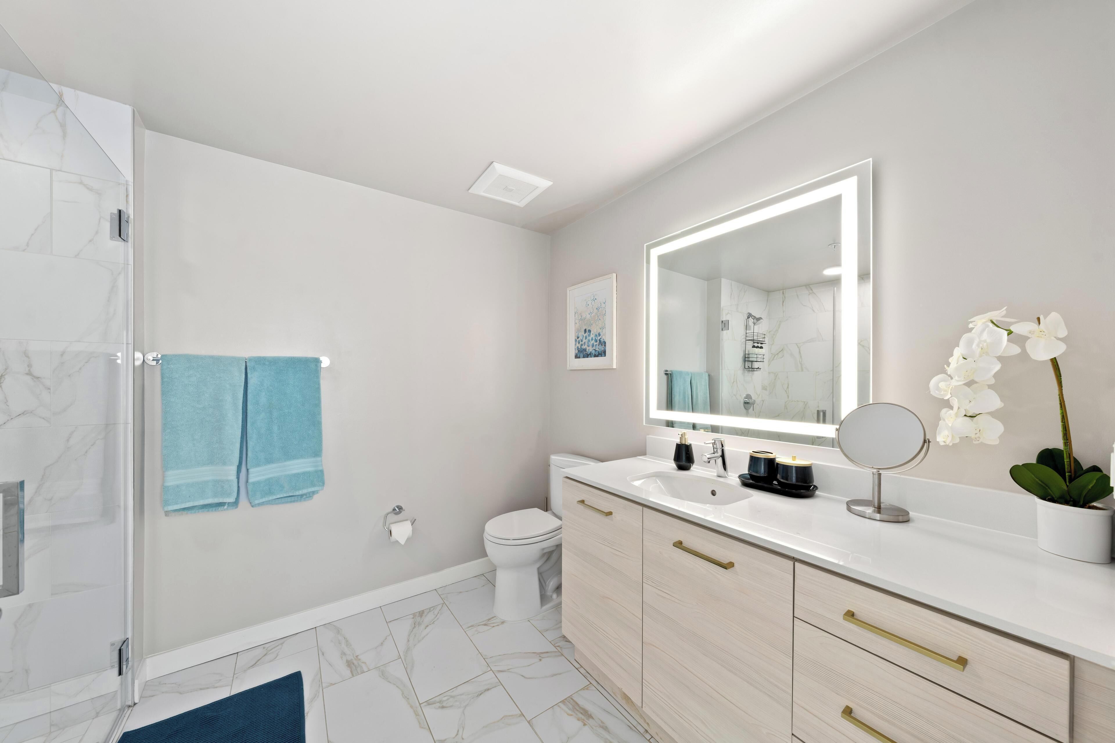 Ein modernes Badezimmer mit Dusche, Toilette und Waschtisch mit Spiegel und Waschbecken.