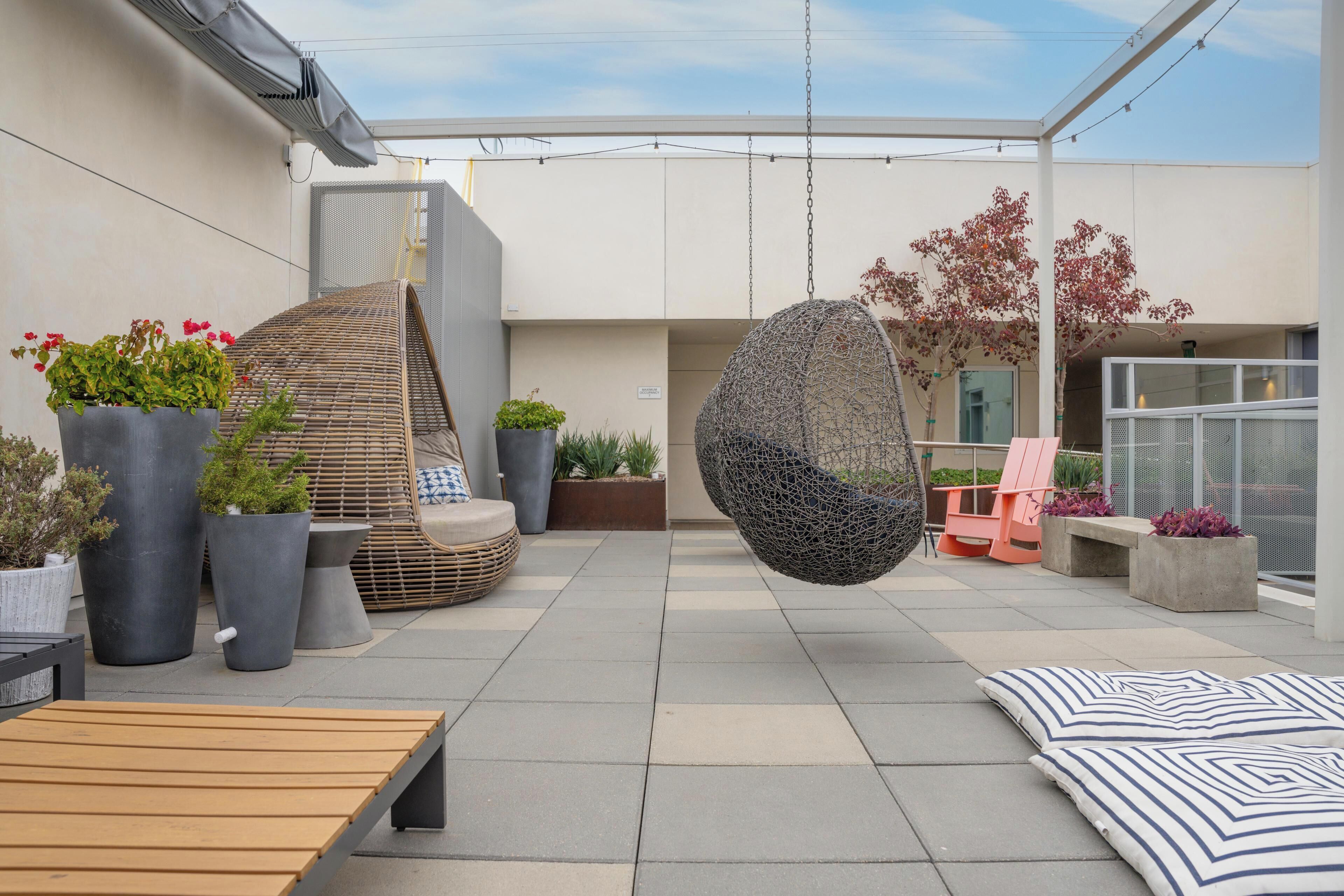 An outdoor patio area with seating, planters, and a hanging chair.